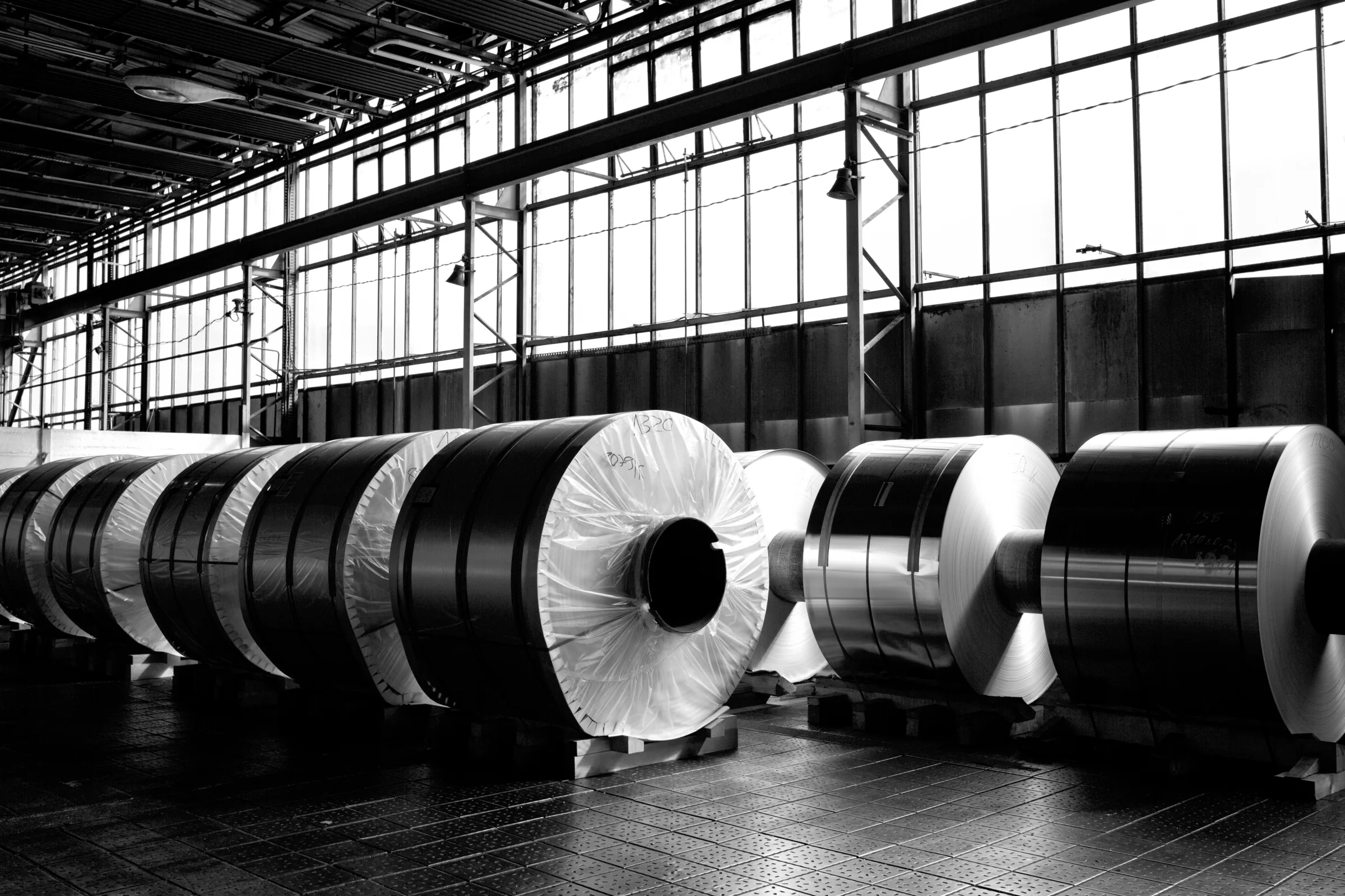 Industriehalle mit großen Metallrollen, Schwarzweiß